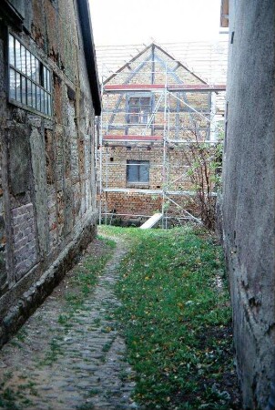 Blick durch Pflastergasse auf eingerüsteten Hausgiebel