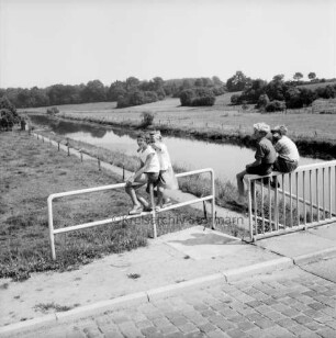 Trave mit angrenzender Knicklandschaft: vorn Brücke der Landstraße Richtung Reecke (Hansestadt Lübeck): Kinder auf Geländer
