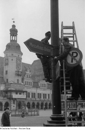 Arbeiter beim Anbringen von Hinweisschildern für die Herbstmesse 1953