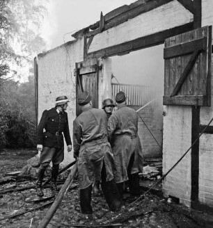 Schleushörn: Brand: Trabergestüt und Reitstall "Schleushörn" von Klaus Martens: brennender Stall mit Reetdach: vorn vier Feuerwehrmänner beim Löschen durch Eingang