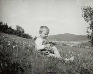 Kleines Kind auf einer Wiese sitzend