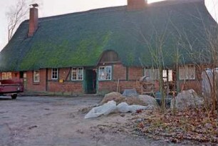 Nütschau: Schloßstraße 42a-c: traufständige Mehrfamilienkate aus Fachwerk mit Reetdach: Sanierung: Straßenfront: Eingangstüren, Sprossenfenster, Heuluke: vorne Baumaterialien, Sandhaufen, Betonmischer: 3. Februar 1994
