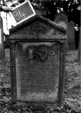 Grabstein 94 (Index: 100111195) Material: Sandstein Zustand: leicht verwittert Maße HxBxT: 103x62x14 cm Beschreibung: ädikulaartige Stele mit Halbsäulen, giebelartiger Abschluß mit Verdachung Symbolik: segnende Hände: Grabstein 94