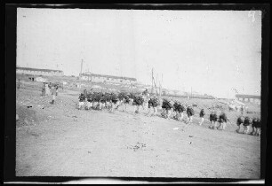 Nador (Marokko): "Kirchenparade zur Feldmesse" der Infanterie [des spanischen 10. Kavallerie-Regiments "Alcántara" (?)] in hellgestreiften Uniformhosen, dunklen Uniformjacken, Tropenhelmen und Marschgepäck bei einer Richtungsänderung auf einer Ortsstraße mit Gebäuden im Hintergrund