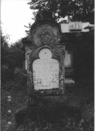 Grabstein 41 (Index: 99799491) Material: Sandstein, Schriftplatte Marmor Zustand: verwittert Maße HxBxT: 156x60x24 cm Beschreibung: Stele mit eingezogenem Stelzbogenabschluß, Verdachung, Palmettenaufsatz, Schriftplatte eingelassen mit Kleeblattabschluß, breiter Sockel Symbolik: floral: Grabstein 41