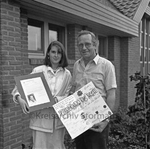 Freiwillige Feuerwehr (Ortswehr) Rethwischfeld: Louise Ducker überreicht Ortswehrführer Hans Jascobsen ein Foto mit Autogramm von Margaret Thatcher, Premierministerin des Vereinigten Königreichs, einen Brief der britischen Regierung und ein Plakat mit Unterschriften von britischen Feuwerwehrleuten