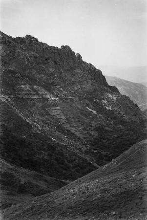 Steinwall : Eine Straße im Gebirge wird durch Steinwälle vor Erosion geschützt.