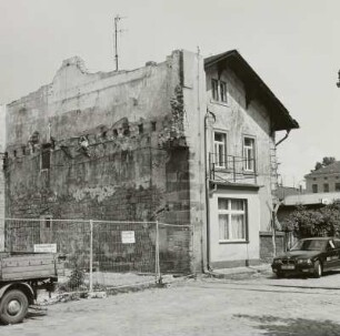 Kreuzung einer Werkstraße mit einem Anschlußgleis in ein (devastiertes) Fabrikgebäude, daneben Kontorgebäude (?)