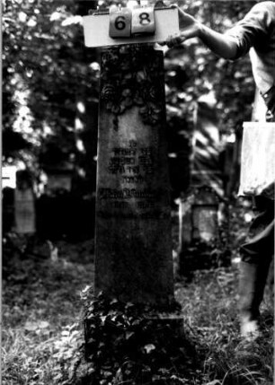 Grabstein 68 (Index: 100109315) Material: Sandstein (?), Sockel Kalkstein Zustand: gut Maße HxBxT: 129x30x12 cm Beschreibung: Obelisk, getreppter Sockel, unterer Sockelteil rustica Symbolik: Rosen Steinmetz: Beerli Besonderheit: Nummer auf Rückseite: 164: Grabstein 68