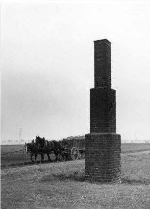 Deutschland? Gemauertes Postament (Backstein) neben einem Feldweg. Ansicht mit Pferdefuhrwerk beim Einbringen der Ernte