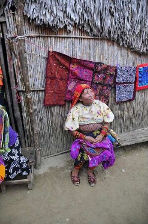 Kuna Yala - Kuna-Indianerin mit Mola Kunstwerken : Eine Kuna-Indianerin sitzt vor ihrer Wohnhütte, im Hintergrund sind textile Mola-Kunstwerke zu sehen. Aufgenommen am 12. September 2011 auf einer der San Blas Inseln im autonomen Gebiet der Kuna-Indianer vor der Atlantikküste der Republik Panama