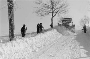 Reportage "Was kostet der Schnee?". Schneepflug im Einsatz. Ansicht mit Hilfskräften