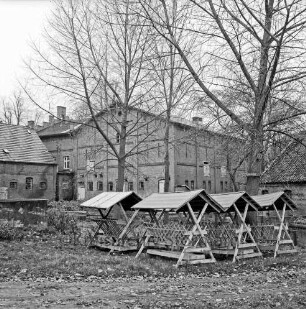 Grönwohldhof: vorn rechts Raufen für Wildfütterung: dahinter Bäume: hinten Hofgebäude