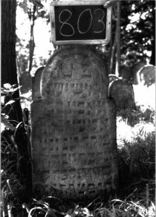 Grabstein 803 (Index: 100105074) Material: Sandstein Zustand: leicht verwittert Maße HxBxT: 82x38x8 cm Beschreibung: Stele, unregelmäßiger und überhöhter eingezogener Rundbogenabschluss (beinahe Hufeisenbogen), angedeuteter umlaufender Rahmen: Grabstein 803