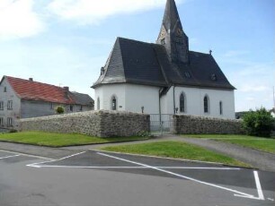 Evangelische Kirche-Ansicht von Nordosten mit Kirche (Gotische Gründung 15 Jh) mit Dachturm über Kirchhofmauer (Wehrgang mit Steinbrüstung und Schießscharten abgetragen)