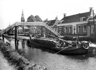 Niederlande. In der Provinz Groningen. Ein Frachtkahn befindet sich auf einer typischen hollänischen Gracht.