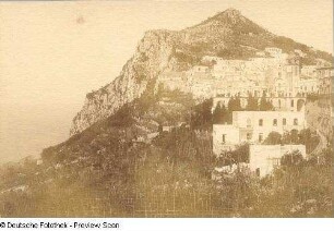Capri. Ortsteilansicht mit Uhrturm an der Piazetta und Via Aquaviva. Blick zum Monte San Michele