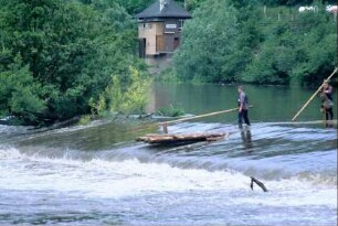 Floß mit Flößern beim Durchfahren der Staustufe