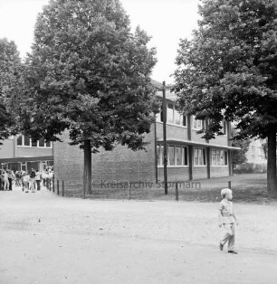 Grundschule: Soltausredder: Erweiterungstrakt nach Inbetriebnahme: davor Schulhof mit Bäumen: vorn rechts und hinten links Schulkinder