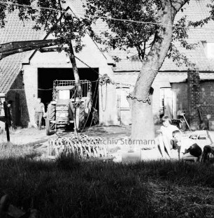 Bauerngehöft Herbst mit landwirtschaftlichen Gerätschaften: rechts neben Baum spielende Kinder: links in Tor Mann neben Trecker