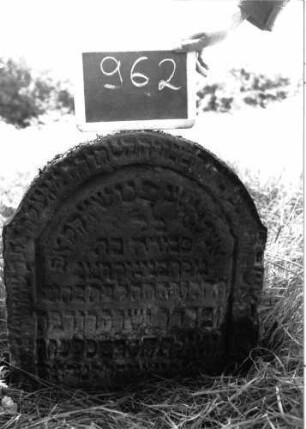 Grabstein 962 (Index: 100103880) Material: Sandstein Zustand: leicht verwittert, eingesunken Maße HxBxT: 63x58x6 cm Beschreibung: Stele, Konvexbogenabschluss, Schriftfeld eingetieft: Grabstein 962