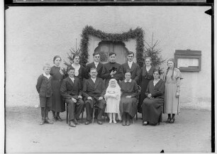 Primizfeier Ruf-Eisele in Sigmaringendorf 1936; Neupriester mit Verwandten und Primizbräutchen vor geschmücktem Hauseingang