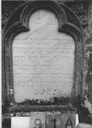 Grabstein 91 (Index: 99800133) Material: Sandstein, Schriftplatte Marmor Zustand: verwittert Maße HxBxT: 180x63x22 cm Beschreibung: Stele, Mittelerhöhung, Verdachung m. Zinnenaufsatz, eingelassene Schriftplatte mit Kleeblattbogenabschluß Symbolik: floral: Grabstein 91A