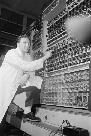 Elektronenrechner auf Röhrenbasis. Mitarbeiter vor der Hardware stehend