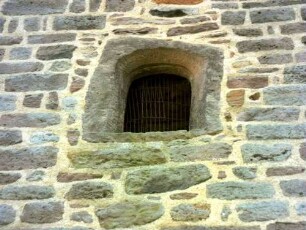 Evangelische Kirche - Kirchturm von Norden (romanisch gegründet) - Mittelgeschoß mit Werksteinen im Mauersteinverband und zu gotischer Zeit eingesetztem Fenster (Überarbeitung des Kirchturms)