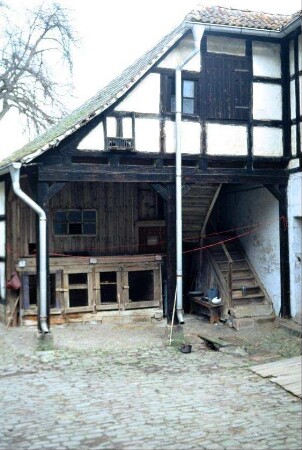 Innenhof eines Gehöftes mit Pflasterung; Holzställe