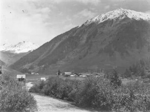 Im Tal : Blick über ein Tal mit Hütten. Hohe Berge im Hintergrund