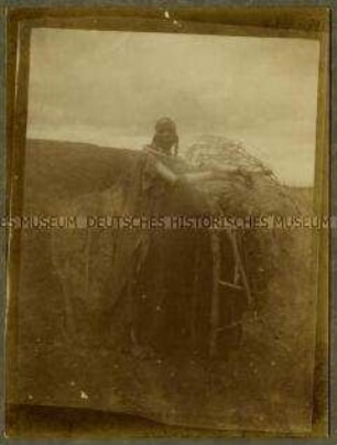 Junge Massai-Frau vor dem Eingang einer kleinen Enkang-Hütte