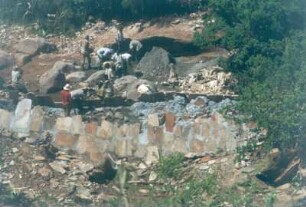 Kenia. Lumbwa-Erddamm Baustelle. Arbeiter beim Errichten einer Grundwassersperre aus Beton und Natursteinen in einem Fluß