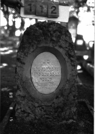 Grabstein 112 (Index: 100105359) Material: Muschelkalk, weiße Marmorplatte Zustand: gut Maße HxBxT: 84x47x28 cm Beschreibung: grob stelenhaft behauener Stein, ovale Schriftplatte: Grabstein 112