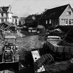 Firma Carl Hoffmann: Hindenburgstraße: Elektrohandel: Abriss des Firmengebäudes: Bauschutt mit Bretterhaufen: dazwischen Bagger und Lkw: hinten links Wohn- und Geschäftshaus mit Drogerie Purnhagen: hinten rechts Wohn- und Geschäftshaus mit Haushaltswarenhandlung Otto Möller: dazwischen Marktplatz mit Rathaus und Stadthaus, Wohnhaus an Hagenstraße