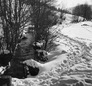 Winterbilder. Trampelpfad im Schnee neben einem Bachlauf