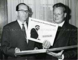 Ein Vertreter der Deutschen Grammophon überreicht Willy Brandt die Schallplatte "Kennedy in Deutschland"
