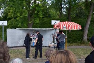 Bad Oldesloe: Kindervogelschießen: Exer: Vogel für die weiblichen Teilnehmerinnen: Teilnehmerin beim Anlegen, im Hintergrund Geschossfang, rechts Aufsichtspersonen mit zweiter Armbrust: 13. Juli 2023