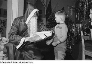 Weihnachtsmann beim Überreichen von Geschenken an Kinder auf der Weihnachtsfeier des VEB Kartographie