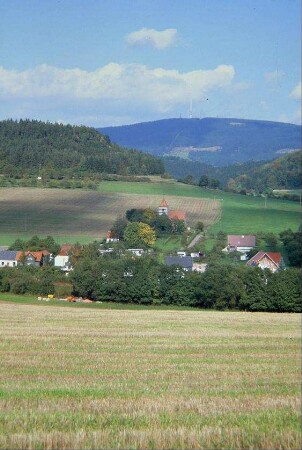 Blick über einen Teil des Dorfes, am Rande Kirche, im Hintergrund Bleßberg