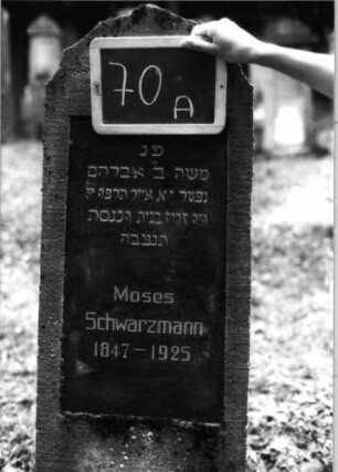 Grabstein 70 (Index: 100090758) Material: Kalkstein mit schwarzer Marmorplatte Zustand: Schrifttafel gebrochen Maße HxBxT: 169x51x22 cm Beschreibung: Stele, getreppter Sockel, geschwungener Rundbogenabschluß, Schrifttafel rechteckig: Grabstein 70A