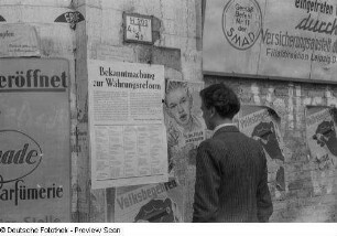 Ein Mann liest ein Plakat zur Währungsreform