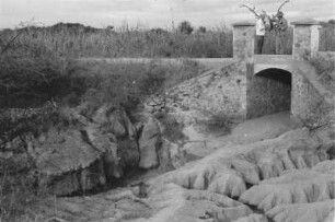 Brücke : Brücke über einen ausgetrocknetetn Flusslauf, darauf zwei Personen.