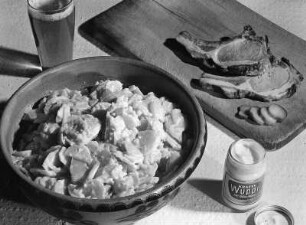Krafts Rezeptaufnahmen. Schale mit Kartoffelsalat, Brett mit Koteletts, Glas mit "Kraft's Wuppi" und Glas mit Bier