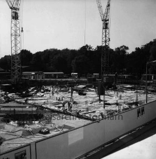 Kreissparkasse Stormarn: Hagenstraße: Blick auf Baustelle mit Fundamentarbeiten: dazwischen Arbeiter: hinten rechts und links Baukräne: dahinter Gewerbegebäude und Schuppen: vorn Bauzaun mit Plakaten der Sparkasse: hinten Bäume des Bürgerparks