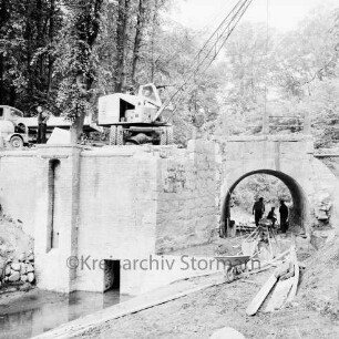 Brücke des Mühlenredder über dem Abfluss des Schlossgrabens: Renovierung: Seitenansicht von Süden: kein Durchfluss, Pumpe: Kran mit Greifarm, Arbeiter, Schubkarre, Baumaterial