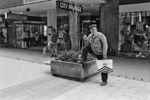 Rauchender Mann mit Einkaufstasche. Vor dem Eingang zur City-Passage
