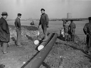 Rohre werden durch die Elbe verlegt. Zukünftig dienen sie zum Transport von Gas. Beobachter schauen dem Geschehen zu