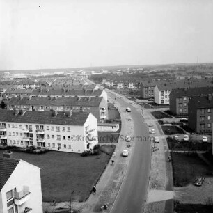 Gartenstadt Falkenberg: Blick vom Rathaus Richtung Osten: Stonsdorfer Weg mit parkenden Pkws auf Seitenstreifen: rechts und links Wohnblocks: dazwischen Grünflächen: im Hintergrund das Gewerbegebiet Stonsdorf