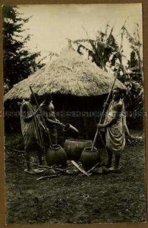 Drei afrikanische Männer beim Kornmahlen